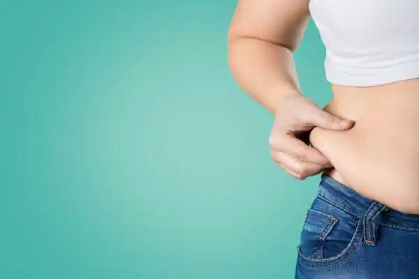 Image of woman pinching her love handles to show weight gain Croydon